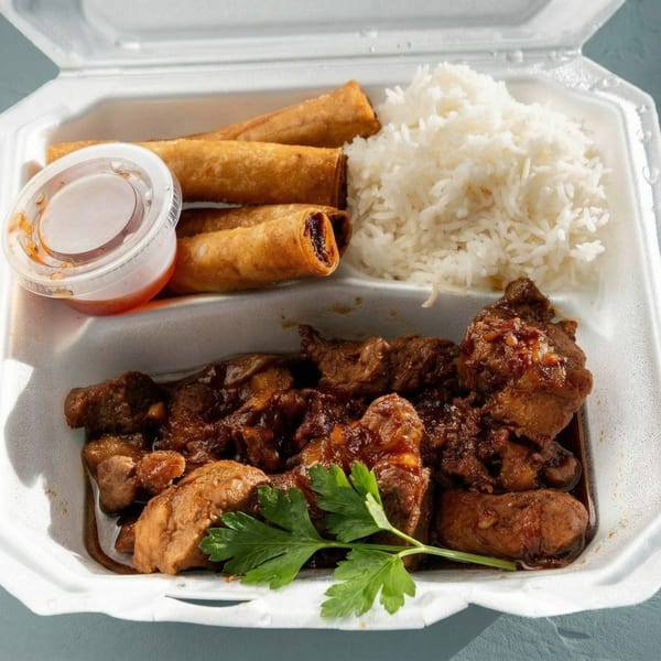 Takeout container with dark meat chicken, white rice, three egg rolls, and a side of sauce.